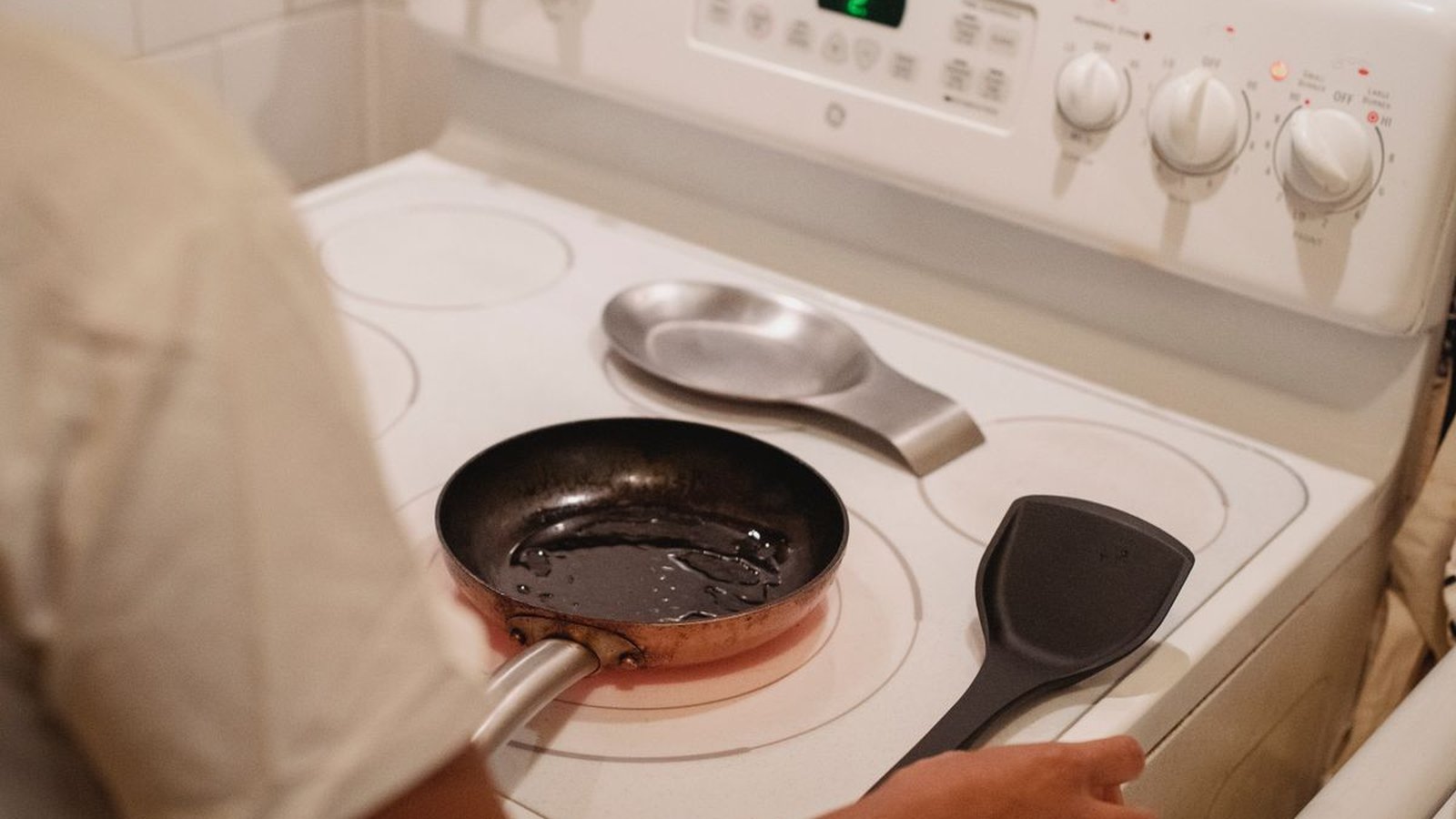 Memasak dengan wajan di atas kompor di dapur rumah